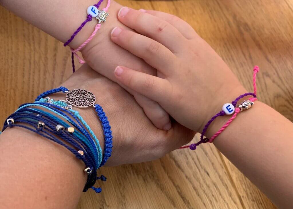 Three hands stacked together, an adult hand and two smaller hands.
