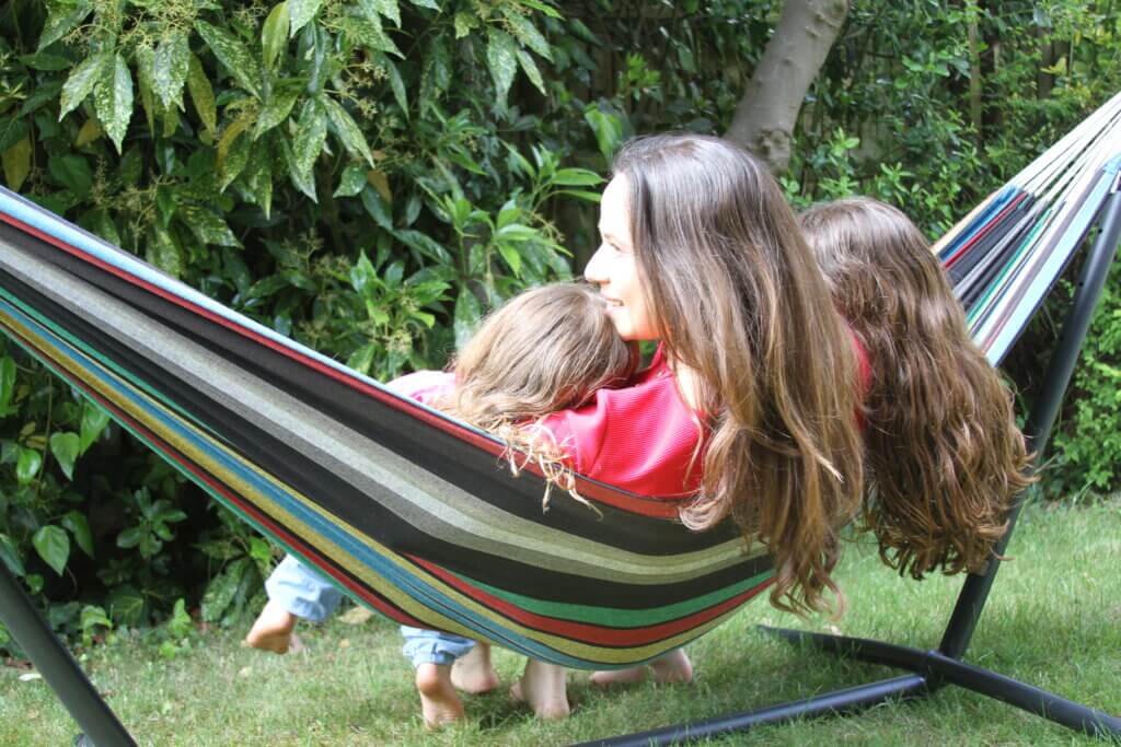 Mother and daughter sitting together on a hammock, sharing a quiet moment.