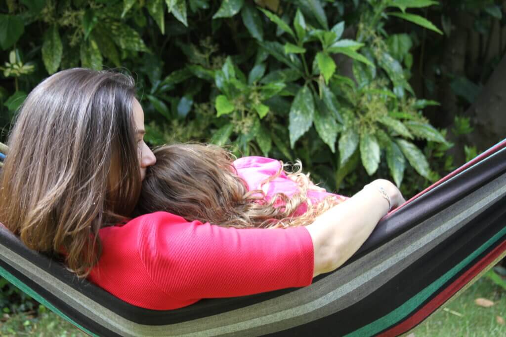 Mother and daughter sitting together on a hammock, sharing a quiet moment.