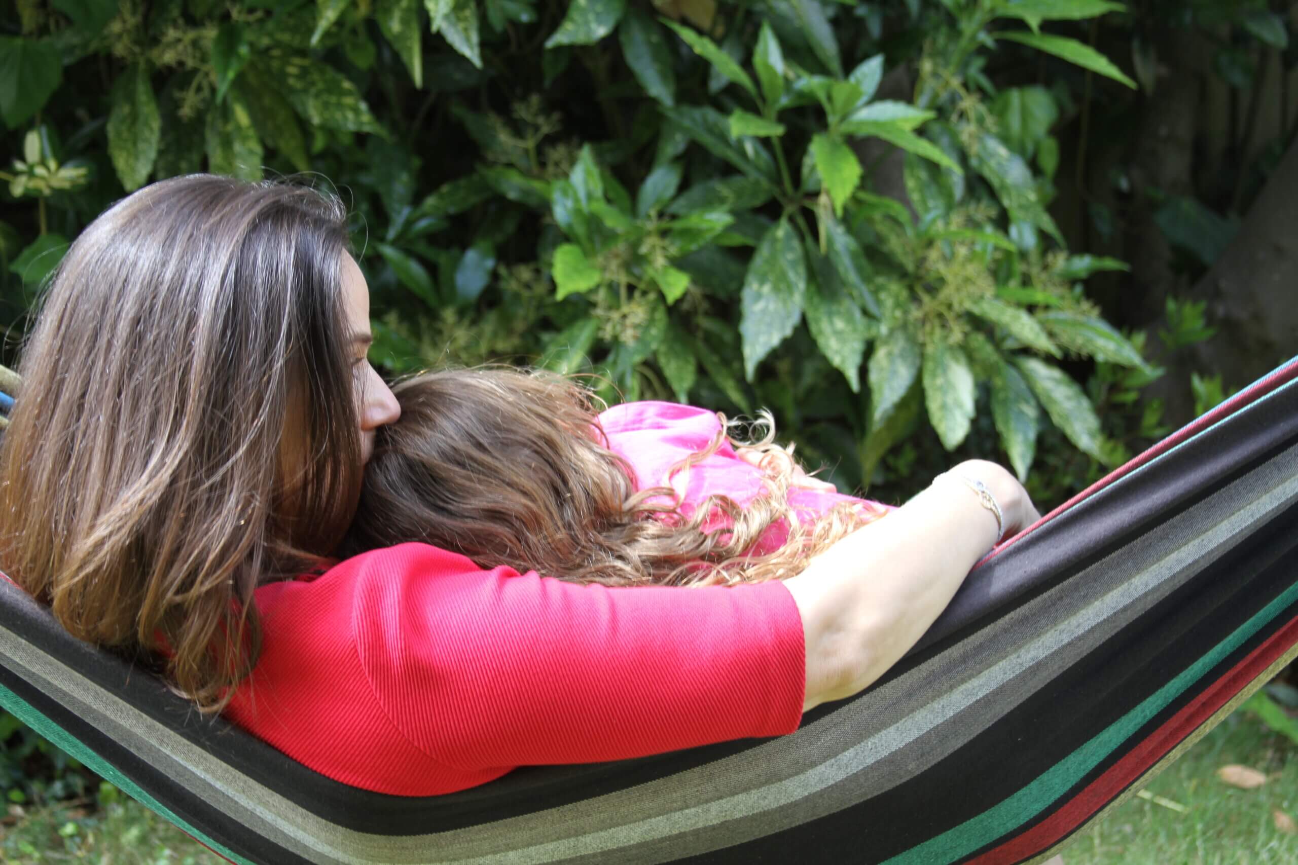 Mother and daughter sitting together on a hammock, sharing a quiet moment.