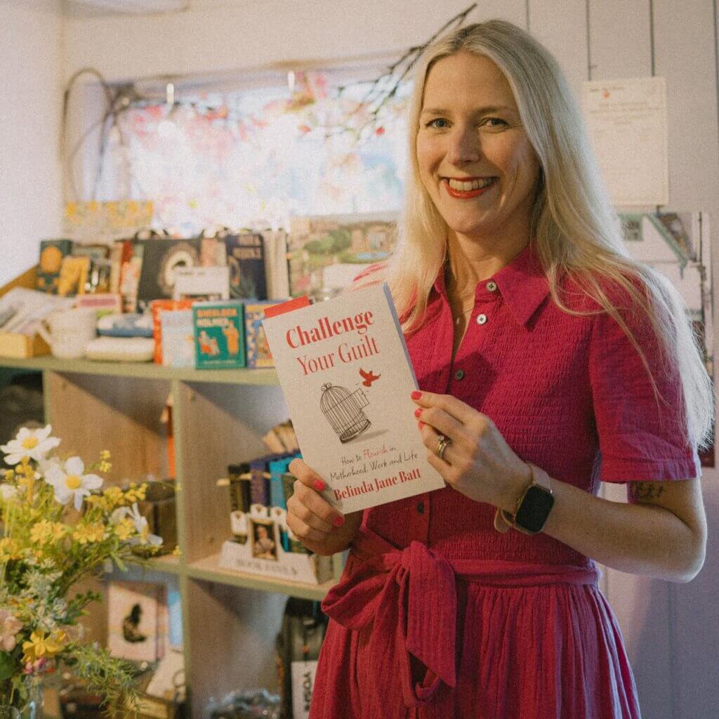 Belinda Jane Batt, author of Challenge Your Guilt, smiling and holding a copy of her book in her hand.